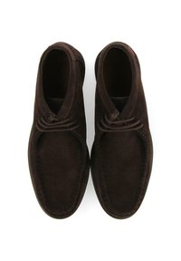 Botas de cuero ante marrón hasta el tobillo con punta redondeada, superficie texturizada y cordones decorativos en la parte frontal. Detalles de costura a lo largo de los bordes.