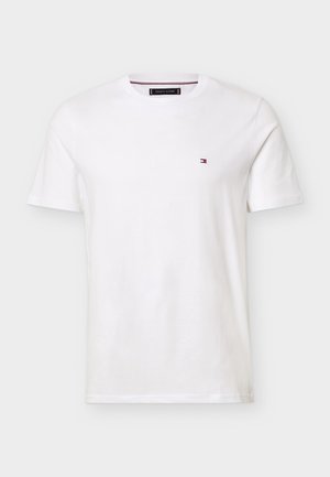 Valge lühikeste varrukatega, ümara kaelusega T-särk, millel on vasakul rinnal väike ristkülikukujuline punase, valge ja sinise värvusega logo.