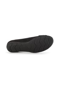 Zapato plano de ante negro con suela de goma texturizada, que presenta un pequeño detalle decorativo en la punta y una forma ligeramente redondeada.