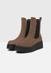 Brune ruskind ankelboots med elastiske sidelapper, kraftige sorte platformsåler og ribbet detaljer på sålen. Glat tekstur generelt.