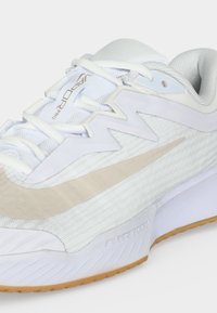 Λευκό αθλητικό παπούτσι Nike Air Zoom με μπεζ σήμα, διχτυωτό πάνω μέρος, λευκά κορδόνια και υφασμένη σόλα με έξω σόλα από καουτσούκ.