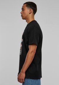 Sort T-shirt med korte ærmer og grafisk design på fronten. Fremstillet af bomuld, med rund halsudskæring og en afslappet pasform.