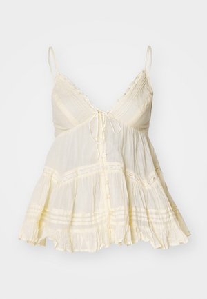 Light yellow sleeveless blouse with a V-neck, adjustable straps, front button closure, scalloped trim, and lace accents. Textured fabric.