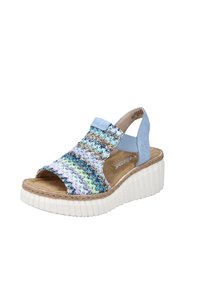 Sandale en tissu tissé dans des couleurs pastel avec un bout ouvert, une sangle réglable et une semelle compensée blanche striée, présentant une finition texturée.