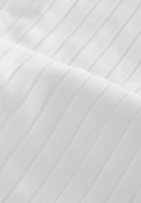 Valkoinen kangas, jossa on pystysuora poimutettu rakenne, sileä pinta ja hienovarainen kiilto. Muotoilu korostaa selkeitä linjoja ja yhtenäistä ulkonäköä.