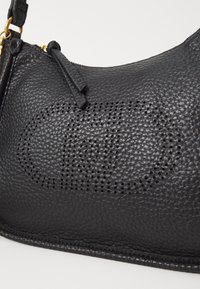 Bolso de mano de cuero negro con una superficie texturizada, que cuenta con detalles ovalados perforados y un acento de hardware en tono dorado.