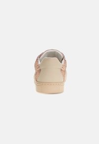 Sneaker beige chiaro con retro in suede testurizzato, decorato con borchie in oro rosa e un interno bianco. Suola in gomma con una grip a motivi.