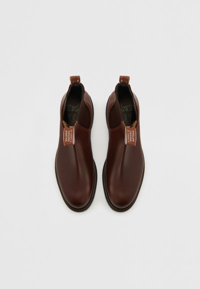 Bottines chelsea en cuir marron avec des panneaux élastiques sur les côtés, des languettes de tirage et des coutures contrastées. Fini lisse avec un design à bout rond.