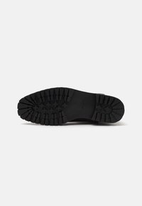 Sole of a black boot with deep treads and cross-shaped patterns, showing brand name "ALDO" in the center.