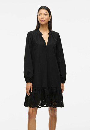 Abito nero realizzato in tessuto leggero, con scollatura a V profonda, maniche lunghe a sbuffo e orlo arricciato con dettagli di intaglio occhiello.