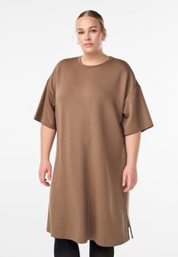 Brun oversized kjole lavet af letvægtsstof, med korte ærmer, rund halsudskæring og sideslidser i kanten for let bevægelse.