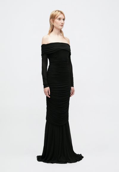 Vestido preto sem mangas com textura franzida. Mangas longas e ajustadas que terminam numa barra rodada, feito de um tecido liso e elástico.