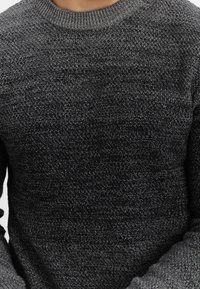 Dunkelgrauer Strickpullover mit strukturiertem Muster, Rundhalsausschnitt und gerippten Bündchen. Das Material wirkt weich und hat ein mittleres Gewicht.