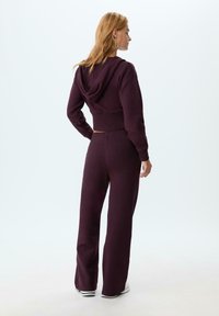 Felpa con cappuccio accorciata e pantaloni a vestibilità ampia in tessuto bordeaux scuro. Texture morbida con vita elastica e polsini a costine.