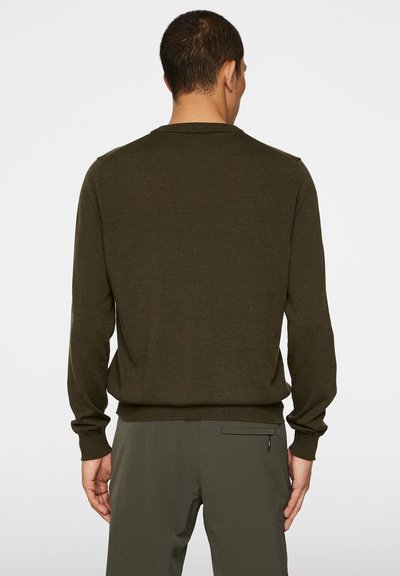 Olivgrön stickad tröja med långa ärmar, rundad hals och ribbade muddar och nederkant. Slät textur, inga synliga mönster eller hårdvara.