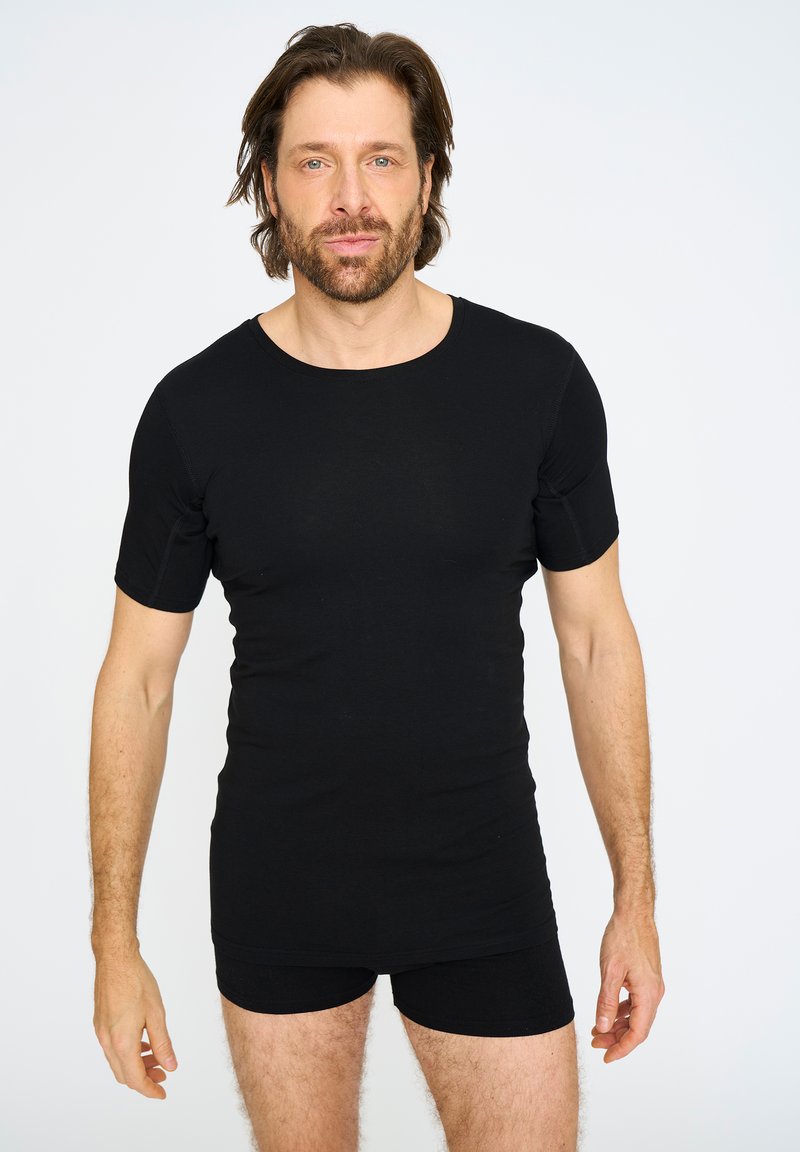 Sort kortærmet skjorte lavet af glat stof, med rund halsudskæring og figursyet design, parret med sorte tætsiddende shorts, der viser en ren silhuet.
