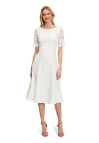 White dress with lace short sleeves, a fitted lace bodice, and a flowy A-line skirt. The material is soft with a smooth drape.