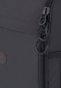 Schwarzer Stoffrucksack mit einem Reißverschluss mit doppelten Ziehgriffen, einem roten kreisförmigen Akzent und einer strukturierten Außenseite.