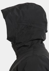 Veste noire imperméable avec une capuche ajustée, tissu texturé et coutures visibles le long de l'ourlet et du col. Aucun motif ni accent présent.