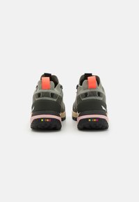Le scarpe da trail running verdi e grigie presentano una suola testurizzata nera, dettagli rosa sul tallone e elementi riflettenti sulla parte superiore.
