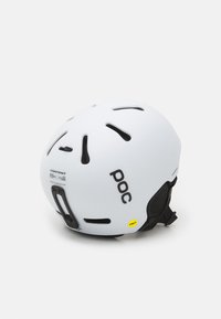 Weißer Helm mit schwarzem Logo und Akzenten, ausgestattet mit Belüftungsöffnungen, einem MIPS-Technologielabel und einem verstellbaren Riemen für einen sicheren Sitz.