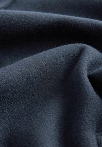 Tela de un azul oscuro con una textura suave y fina, que presenta pliegues suaves y un ligero brillo, sugiriendo un material ligero y cálido.