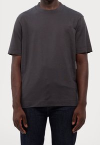 Short-sleeve crew neck t-shirt in dark gray cotton, featuring a subtle logo pattern on the side and a relaxed fit for comfort.