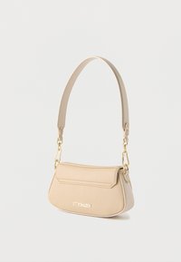 Μπεζ δερμάτινη τσάντα ώμου με χρυσά εξαρτήματα και έναν μόνο ιμάντα, με το λογότυπο "Steve Madden" στο μπροστινό μέρος.