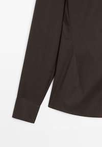 Donkerbruine langekraag shirt met een zachte textuur, enkele knoop bij de mouw en een gebogen zoom met zijnaaddetails.