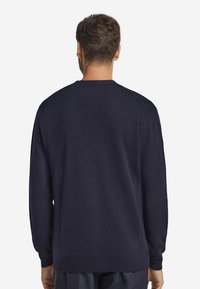 Mörkblå, texturerad tröja med lång ärm och rund halsringning. Har ribbade muddar och nederkant, slät finish.