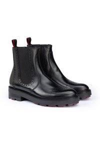 Stivali Chelsea neri in pelle con pannelli elasticizzati, dettagli perforati e accenti rossi sul tallone. Suola in gomma spessa per una buona trazione.