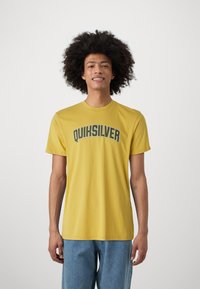 Yellow cotton T-shirt with a round neck, featuring the text "QUIKSILVER" in dark green curved typography across the chest.