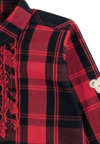 Camicia a quadri rossa e nera con una pettorina arricciata e una patch di un orso crema sulla manica. Realizzata in tessuto di cotone tessuto con una texture liscia.