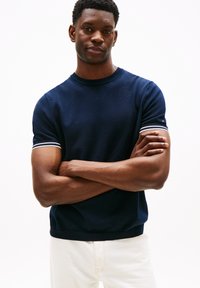 Maglione a maniche corte in maglia di colore blu navy con polsini a righe bianche a contrasto e scollo rotondo, realizzato in un tessuto morbido con un delicato motivo testurizzato.