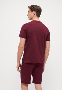 Maroon short-sleeve t-shirt and matching shorts, featuring a simple design, soft texture, and casual fit. No visible logos or patterns.