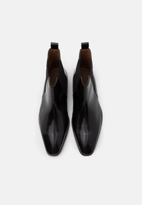 Černé kožené kotníkové boty s špičatou špičkou, elastickými bočními panely a poutky na vytahování. Hladký povrch s lesklým finišem.