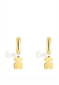 Orecchini a cerchio in oro con un ciondolo a forma di orso bianco. L'orso è fissato con un anello liscio e l'oro lucido crea una finitura riflettente.