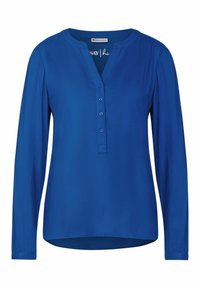 Blusa blu a maniche lunghe in tessuto liscio con scollatura a V e chiusura con bottoni. Presenta quattro bottoni e un orlo leggermente curvato.