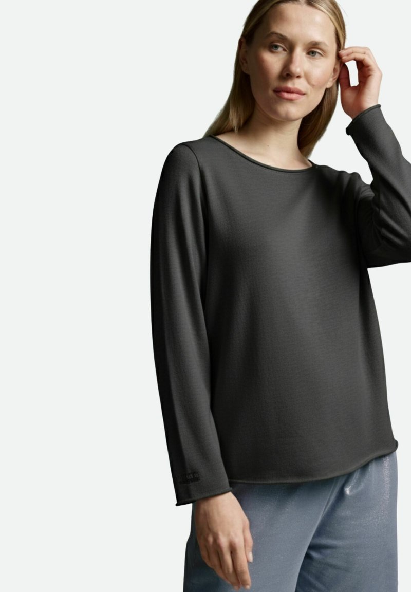 Dunkelgraues Langarmshirt mit rundem Ausschnitt, glatter Textur und lockerem Sitz, kombiniert mit hellblauen glänzenden Hosen.