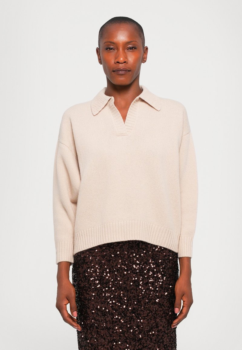 Beige knitted sweater with a collared neckline and ribbed hem, paired with a brown sequin-embellished skirt. Simple, textured design.
