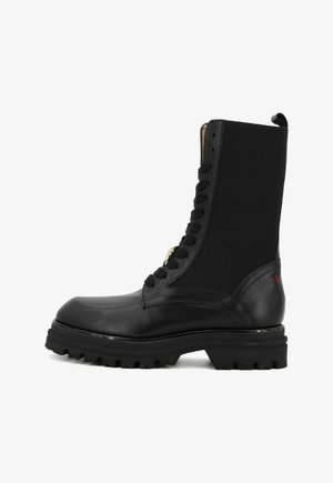 Stivale alla caviglia nero realizzato in pelle e tessuto, con lacci frontali, suola robusta e dettaglio rosso sul lato. Design con gambale alto.