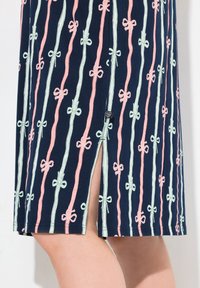 Abito navy con strisce verticali di nastri verde chiaro e rosa con fiocchi. Include uno spacco laterale per un tocco in più. Tessuto in cotone morbido.