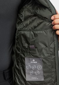 Ciemnozielona ocieplana kurtka od wewnątrz o pikowanej strukturze, posiada etykietę z instrukcjami pielęgnacji oraz kieszeń do przechowywania.