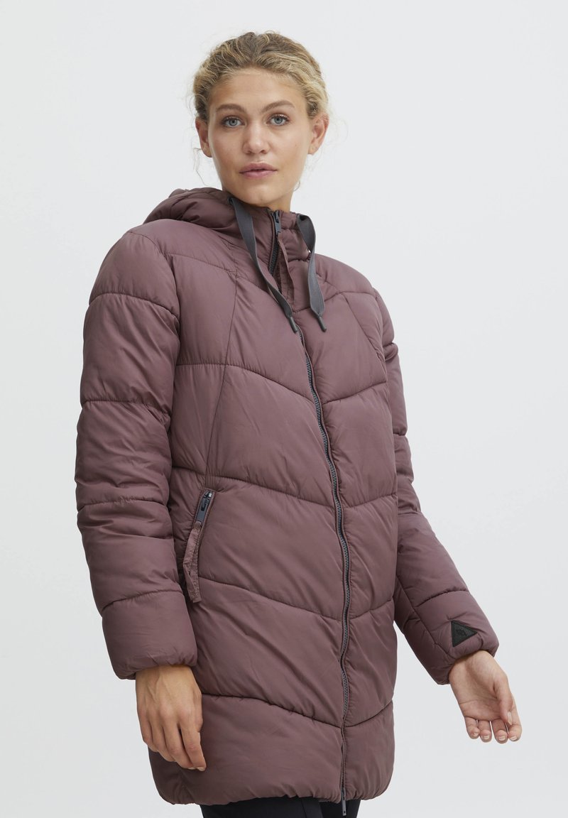 Vadderad kappa i djup mauve med huva, kviltad struktur, framdragkedja och sidofickor. Svarta dragsnören och triangulärt logotypaccent.