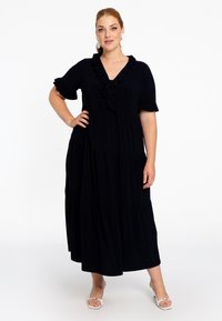 Schwarzes, gestuftes Maxikleid mit kurzen, gerafften Ärmel und V-Ausschnitt, das über ein zentrales Rüschendetail entlang des Ausschnitts verfügt.