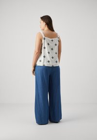 Valge tank-top, millel on musta rombimuster; laiad rihmad ja ruudukujuline selg. Kombineeritud vabalt langevate siniste teksadega. Sile tekstuur.