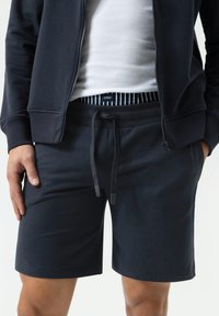 Marineblauwe shorts van een katoenmix met een elastische tailleband, trekkoordsluiting en geribbelde binnenvoering. Heeft een zachte textuur.