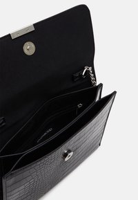 Svart handväska i faux läder med krokodilsmönster, magnetisk knäppning, silverfärgad hårdvara och foder i tyg med en zip-ficka.