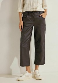 Zwarte neplederen cropped broeken met voorzakken, een knoopsluiting en een relaxte fit, gecombineerd met witte sneakers en een geruite blouse.