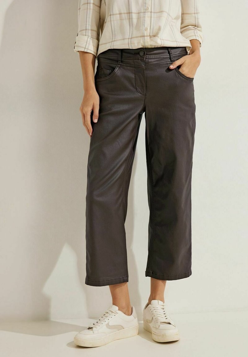 Zwarte neplederen cropped broeken met voorzakken, een knoopsluiting en een relaxte fit, gecombineerd met witte sneakers en een geruite blouse.
